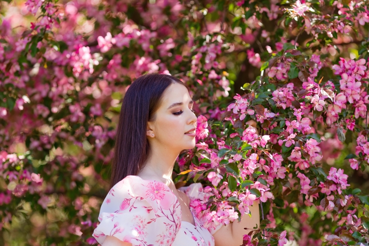 Frau zwischen blühenden rosa Frühlingsblumen | Luminar Blog