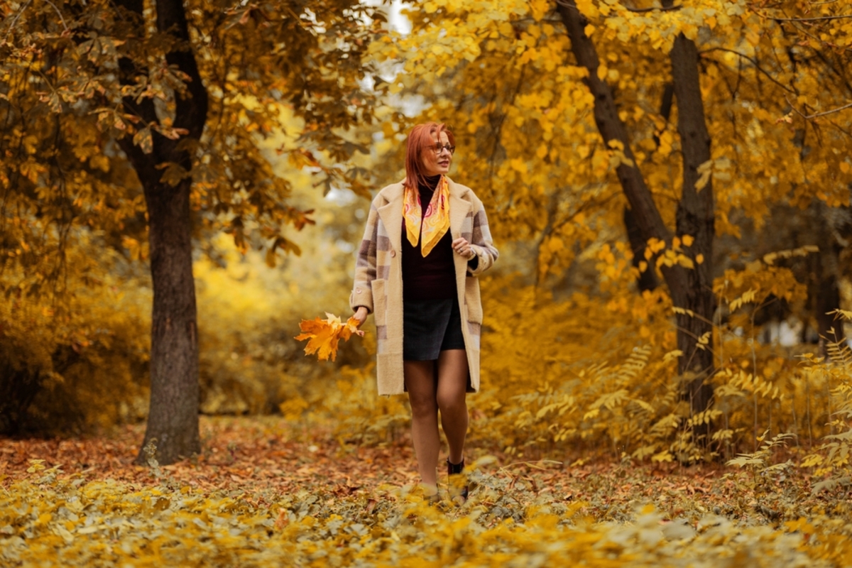 Frau spaziert durch einen Park mit goldenem Herbstlaub | Luminar Blog