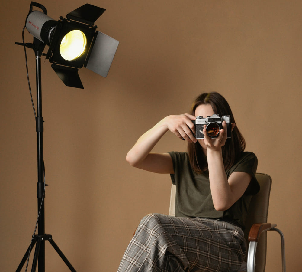 Eine Fotografin sitzt auf einem Stuhl im Studio | Luminar Neo Blog