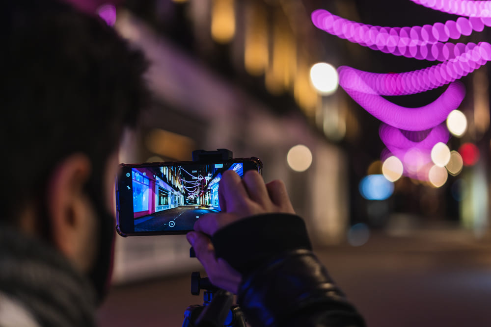 Ein Mann fotografiert eine abendliche, beleuchtete Straße | Luminar Neo Blog 