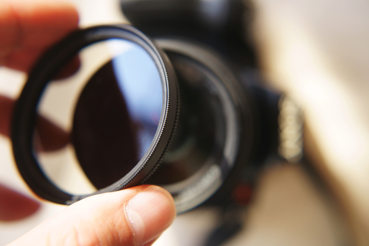 Ein Fotograf setzt einen Filter auf seine Kamera | Luminar Neo Blog