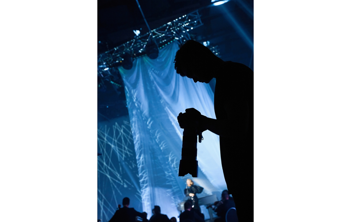 Ein Fotograf betrachtet bei einem Konzert Fotos auf seiner Kamera | Luminar Neo Blog