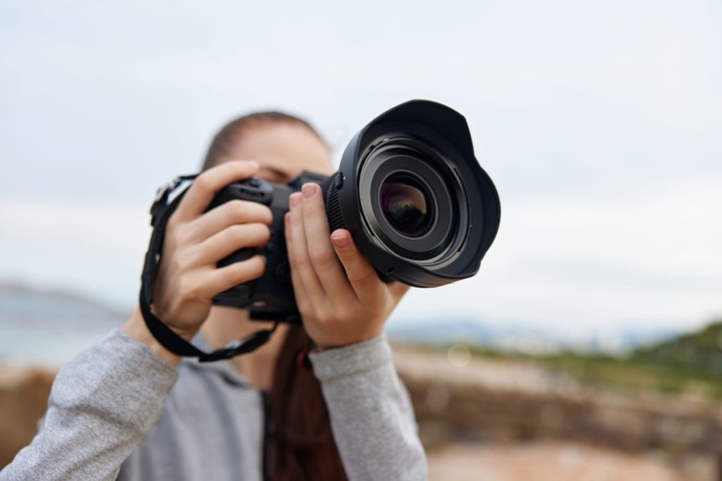 Fotografin hält eine Profikamera mit großem Objektiv | Luminar Neo Blog