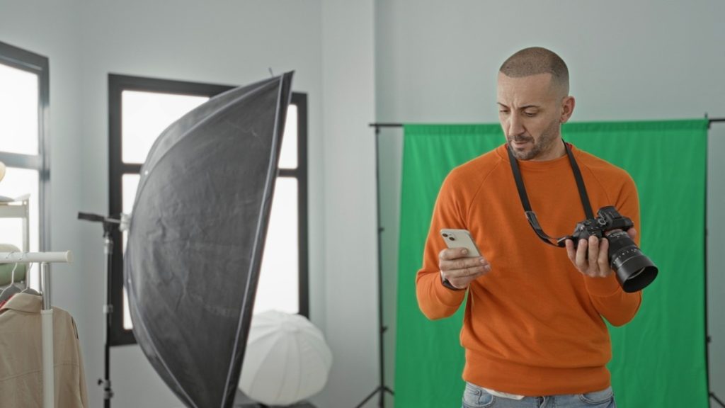 Ein Fotograf mit einer Kamera und einem iPhone in den Händen | Luminar Neo Blog