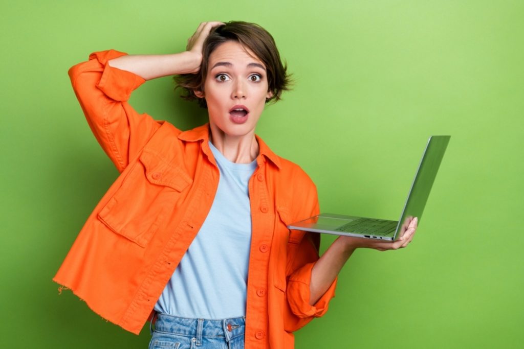 Überraschte Frau mit Laptop vor grünem Hintergrund | Luminar Blog